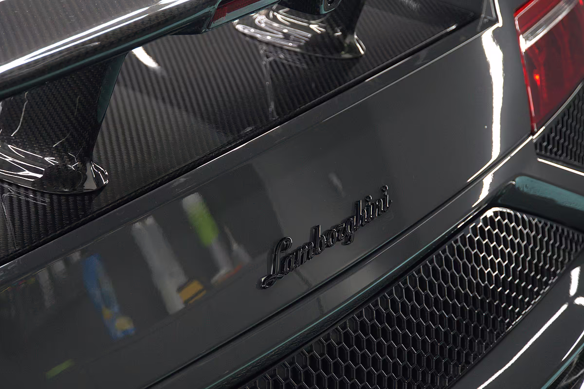 Motorraumdeckel eines Lamborghini mit sichtbarem Köpergewebe unter Klarlack