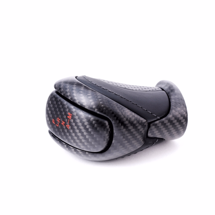 Schaltknauf aus Kohlefaser mit roter Naht und schwarzen Loch und Glattleder. Rotes Schaltschema mit mattem Klarlack. Schaltknauf auf die Seite gelegt